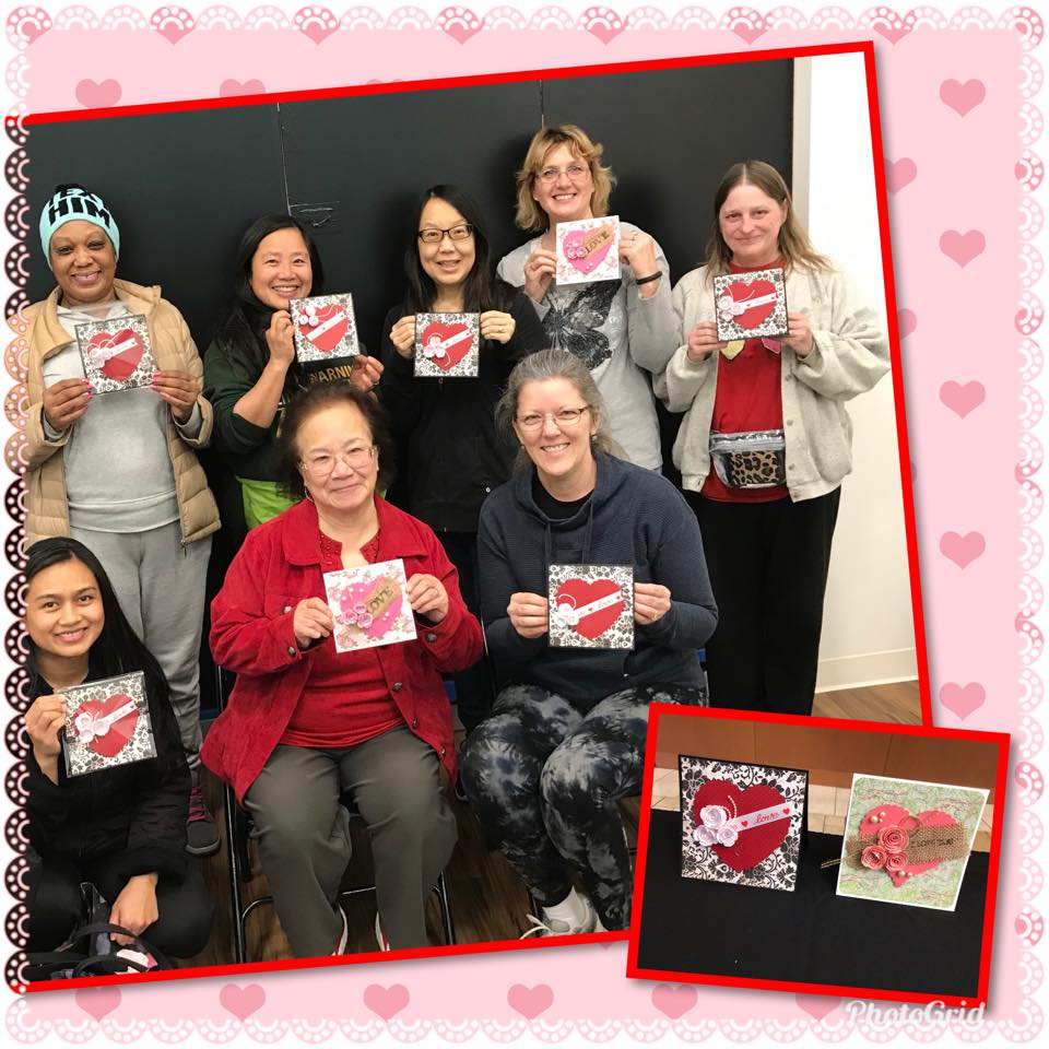 Eight smiling women are showing a heart-theme craft they created in a crafting class. They are standing in front of a dark backdrop and the picture has a red heart border. There is a smaller picture of two heart-shaped pieces of art in the bottom right